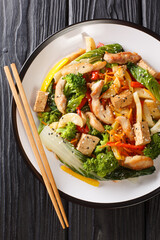 Stir fry vegetables, chicken and tofu close-up in a plate on the table. Vertical top view from above