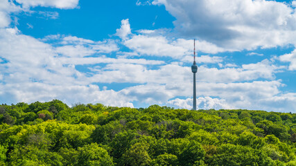 Deutschland, Stuttgarter Fernsehturm, umgeben von endlosen grünen Waldbäumen an sonnigen Tagen, Panorama-Drohne aus der Luft über den Baumwipfeln © Simon