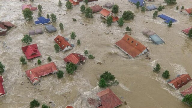 A huge natural disaster shot from the aerial top view—Flood swallows the town, countryside houses are destroyed by the heavy water and collapsed. 