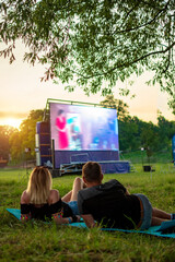 Summer cinema. Couple lying on a blanket watching a movie in the open air