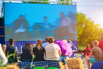 A group of people watching an open-air cinema screen