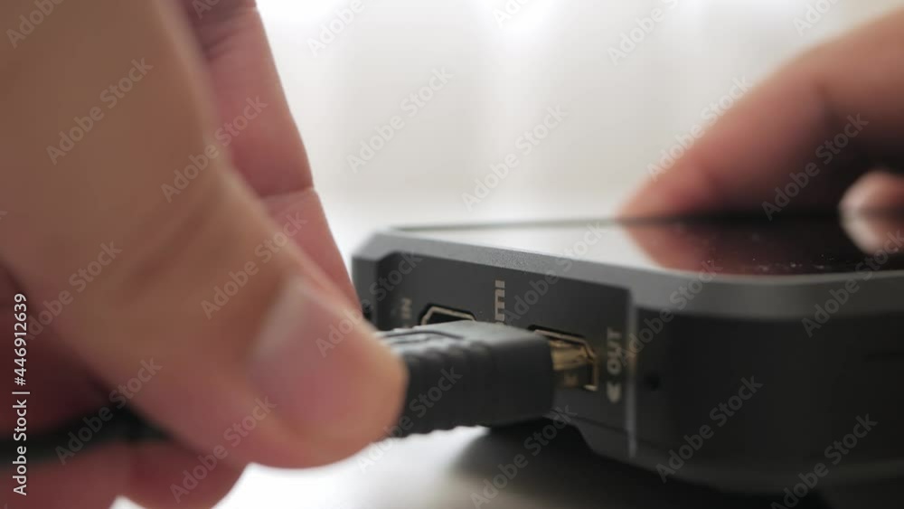 Poster inserting hdmi cable into the side port of external monitor closeup. hdmi cable is inserted into the