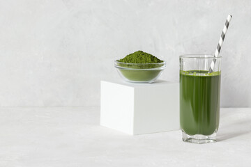 Green drink with chlorella in a glass and powder on a white concrete background. Healthy detox...