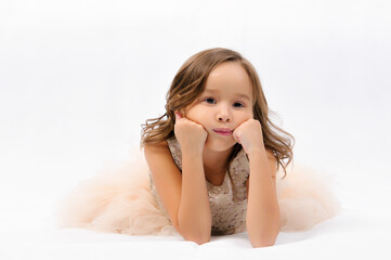 Portrait of happy pretty curly little girl laying on the floor and posing over white background , happy face girl concept