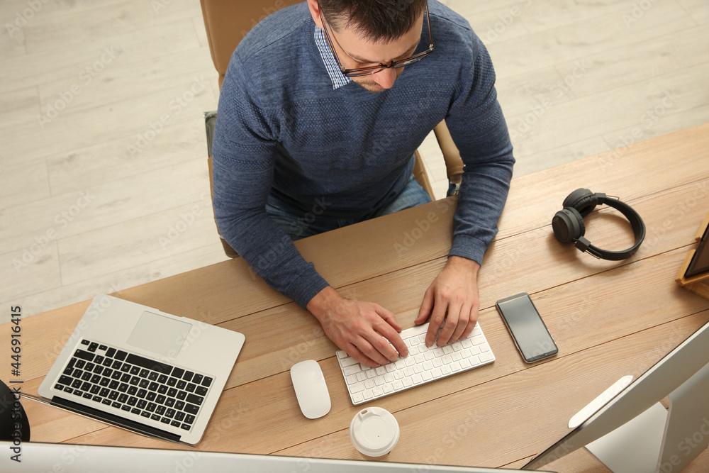 Poster programmer working at desk in office, top view