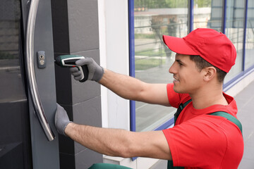 Handyman with screw gun repairing door lock outdoors - obrazy, fototapety, plakaty