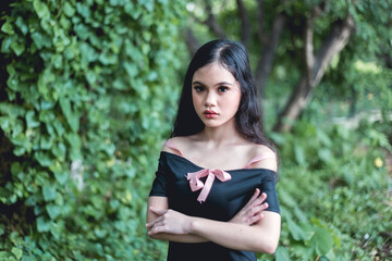 An upset petite Filipina woman in a black top with arms crossed. Irritated due to broken promises...
