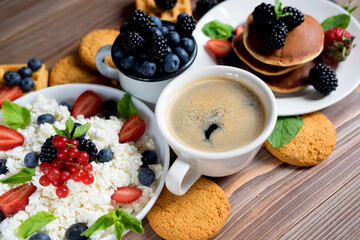 Cottage cheese, coffee, Pancakes for breakfast with blackberries and strawberries.