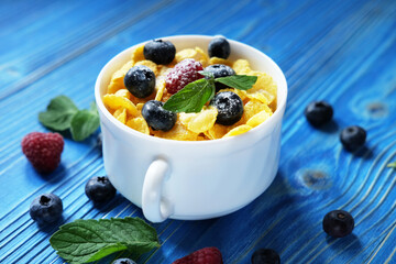 Cornflakes with berries raspberries and blueberries on blue wooden background.