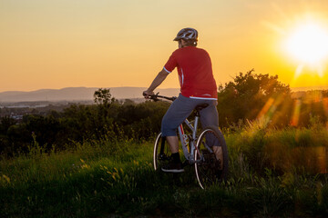 Symbolbild: Mountainbiker genießt die Aussicht bei Sonnenuntergang (model released)