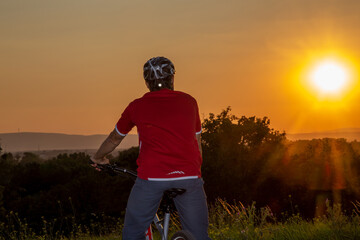 Symbolbild: Mountainbiker genießt die Aussicht bei Sonnenuntergang (model released)