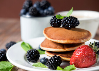 Pancakes for breakfast with blackberries and strawberries. Fluffy and delicious buttermilk pancakes.