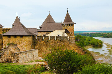 Detailed view of oldl castle in the bank of Dnister River. Ruins of fortifications. High stone walls with massive towers. Blue sky background.  Famous touristic place and travel destination in Ukraine