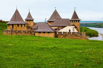 Fototapeta na wymiar Picturesque view of the top of the medieval fortress. Massive stone walls and high towers with wooden roofs. Blue sky background. Famous touristic place and travel destination in Ukraine