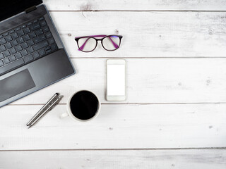 Top view workspace laptop glasses coffee cup and two silver pen with smartphone white screen copy space