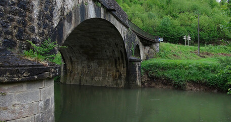 Fototapeta na wymiar old historic heavy stone bridge in the forest, Le Mas d'Azil, southwestern France