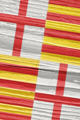 Fragment of the flag of the city of Barcelona on dry wooden surface, cracked with age. It seems to flutter in the wind. Vertical background or backdrop with municipal symbol. Old wood. Hard shadows
