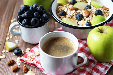 Oatmeal porridge, coffee, apple, berries and nuts on a wooden table.