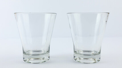 Two clear glasses of whiskey or cocktail on a white background