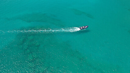 Naklejka premium Aerial drone photo of inflatable rib speed boat cruising in tropical exotic bay with emerald sea
