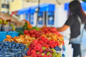 Young woman buying fruit at local farmers market. Fresh organic produce for sale at local farmers market