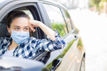 Young woman in a mask sitting in a car