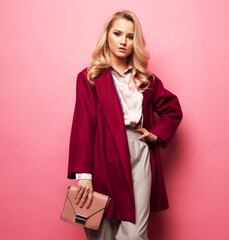 Beautiful woman wear casual coat and holding handbag over pink background