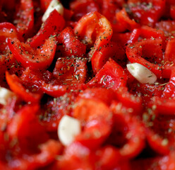 Tomatoes lie on a baking sheet, ready to bake. Sun-dried tomatoes with garlic.