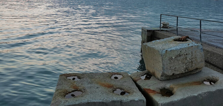 Molo massi e riflessi sull&rsquo;acqua del mare
