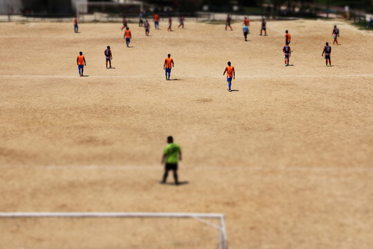 Amateur soccer match on a dirt field in a neighborhood with the tilt shift effect applied to the image
