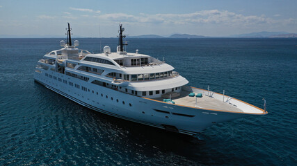 Aerial drone photo of luxury mega yacht with wooden deck and pool facilities anchored in Mediterranean open ocean deep blue bay