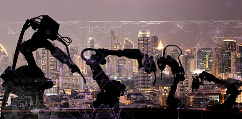 Silhouette of modern automation robot arms with Ai assistant technology network concept and metropolis city building background.