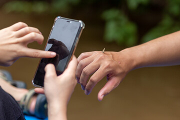 selective focus hand with a small butterfly on hand of tourist hiking and his girlfriend is using a mobile phone to take pictures Holiday activities feel refreshed and relaxed in the natural forest.