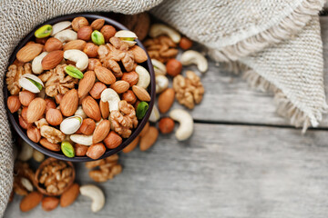 Assorted nuts in a plate on a wooden table with a burlap cloth.