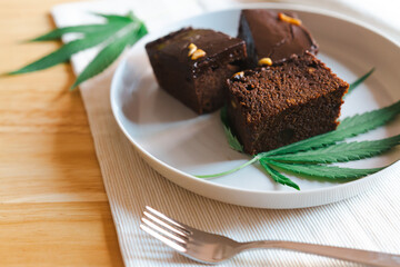 Homemade sweetmeat with marijuana or cannabis leaf on white plate. Alternative medicine concept..