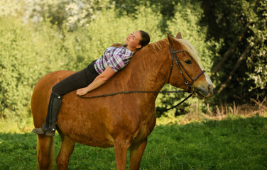 Young Caucasian woman is on a back of her horse in outdoors.