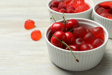 Delicious gummy candies and fresh fruits on white wooden table, closeup. Space for text