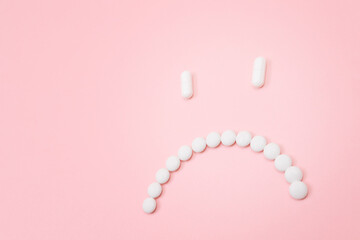 Pharma Harm. Sad Smiley Face Made from White Pills, Lying on Pink Backgrond. Global Pharmaceutical Industry and Medicinal Products
