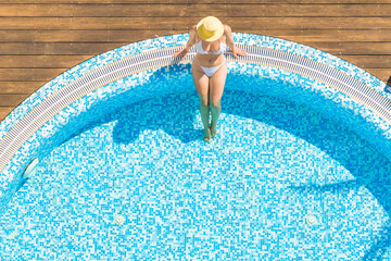Young alone beautiful sports woman in bikini and hat is swimming in hydro massage bath. Aerial...