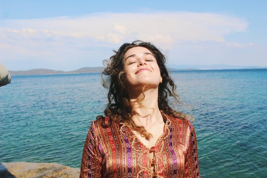 smiling happy portrait of young woman in tradtional turkish y&ouml;r&uuml;k clothing in sea and rocks nature background outfoors sunny day