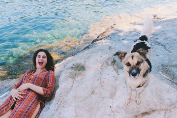 Funny happy Portrait of young woman wearing turkish traditional costume at the sea surprised by stray dog  - obrazy, fototapety, plakaty