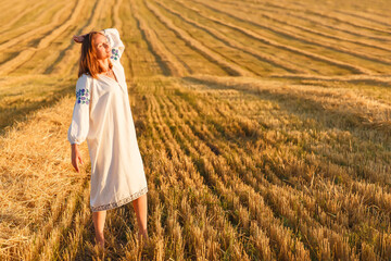 Naklejka na ściany i meble Girl in a wheat field at sunset