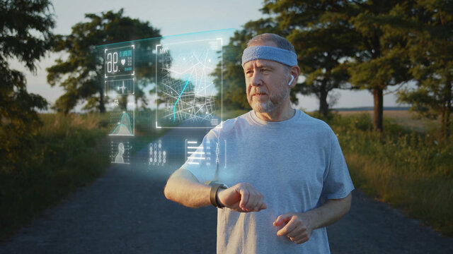 Old caucasian blonde bearded man using smartwatch outside running training sport. Athletic male person checking app notification online. Navigation app, Hologram picture. - Powered by Adobe