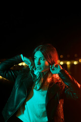 Millennial Girl Enjoying Nightlife In City Street. Youngster Woman Having Fun And Good Mood. Gorgeous Hipster Posing In Colorful Neon Illumination Outdoors. Bokeh Urban Lights