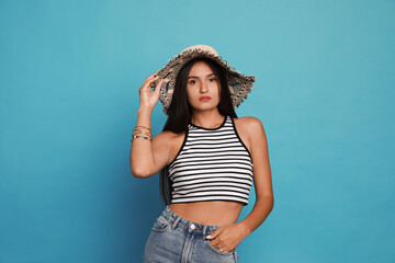 Naklejka premium Beautiful young woman with straw hat on light blue background
