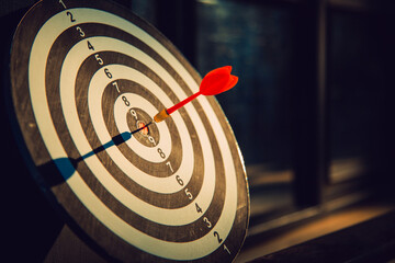 Dart arrow hit on bulleyes of dartboard to represent that the business reached the target  with...