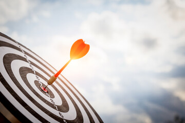 Close up shot red darts arrows in the target  of dartboard center on dark blue sky background....
