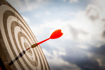 Close up shot red darts arrows in the target  of dartboard center on dark blue sky background....