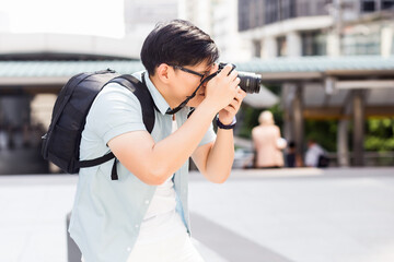 Asian man holding a camera and taking pictures outdoors