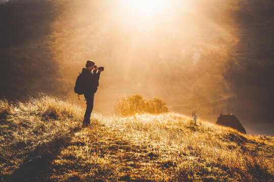 female photographer at sunrise, misty mountains